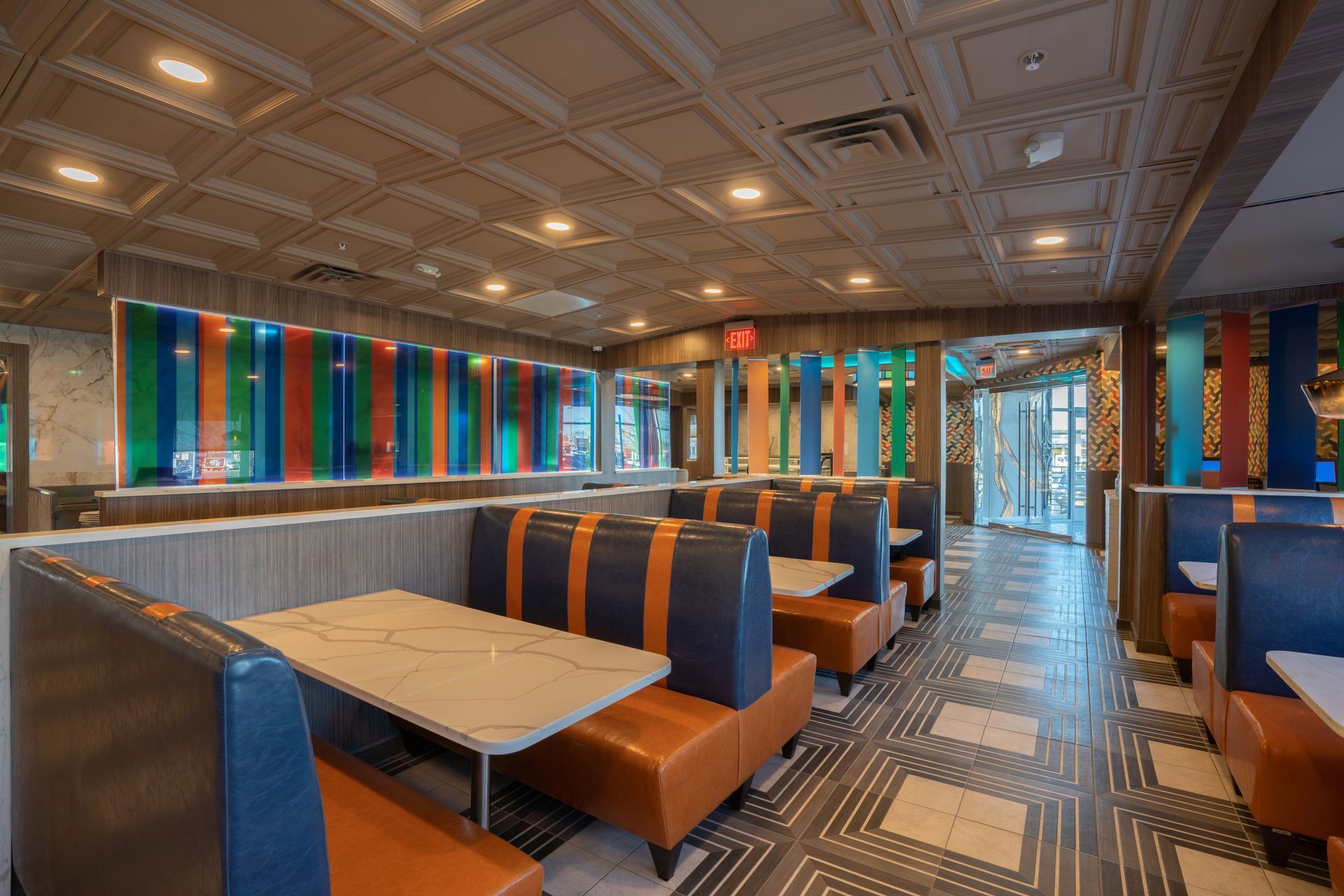 A restaurant with tables and booths and a colorful ceiling.