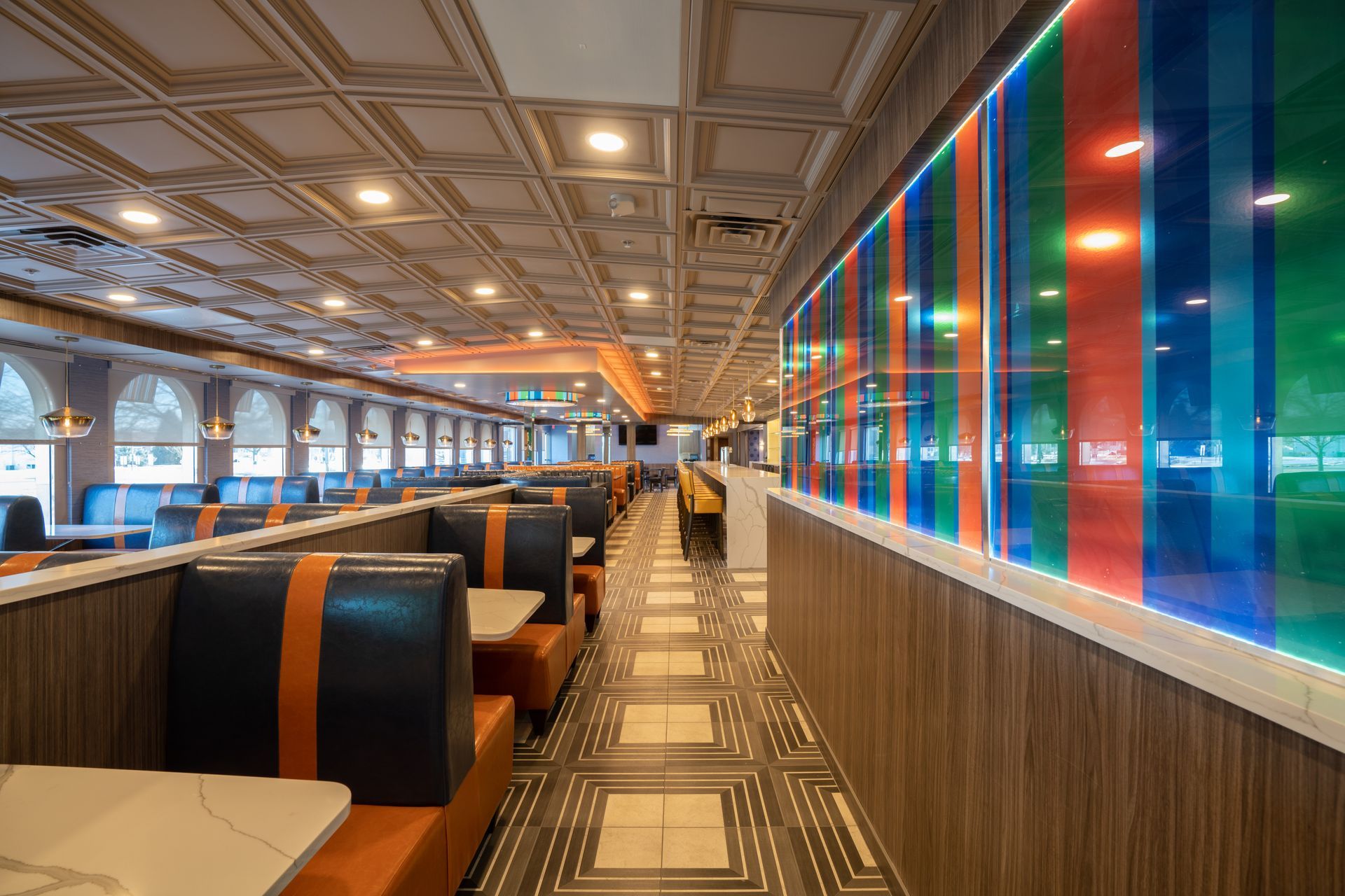 A long hallway in a diner with tables and benches.
