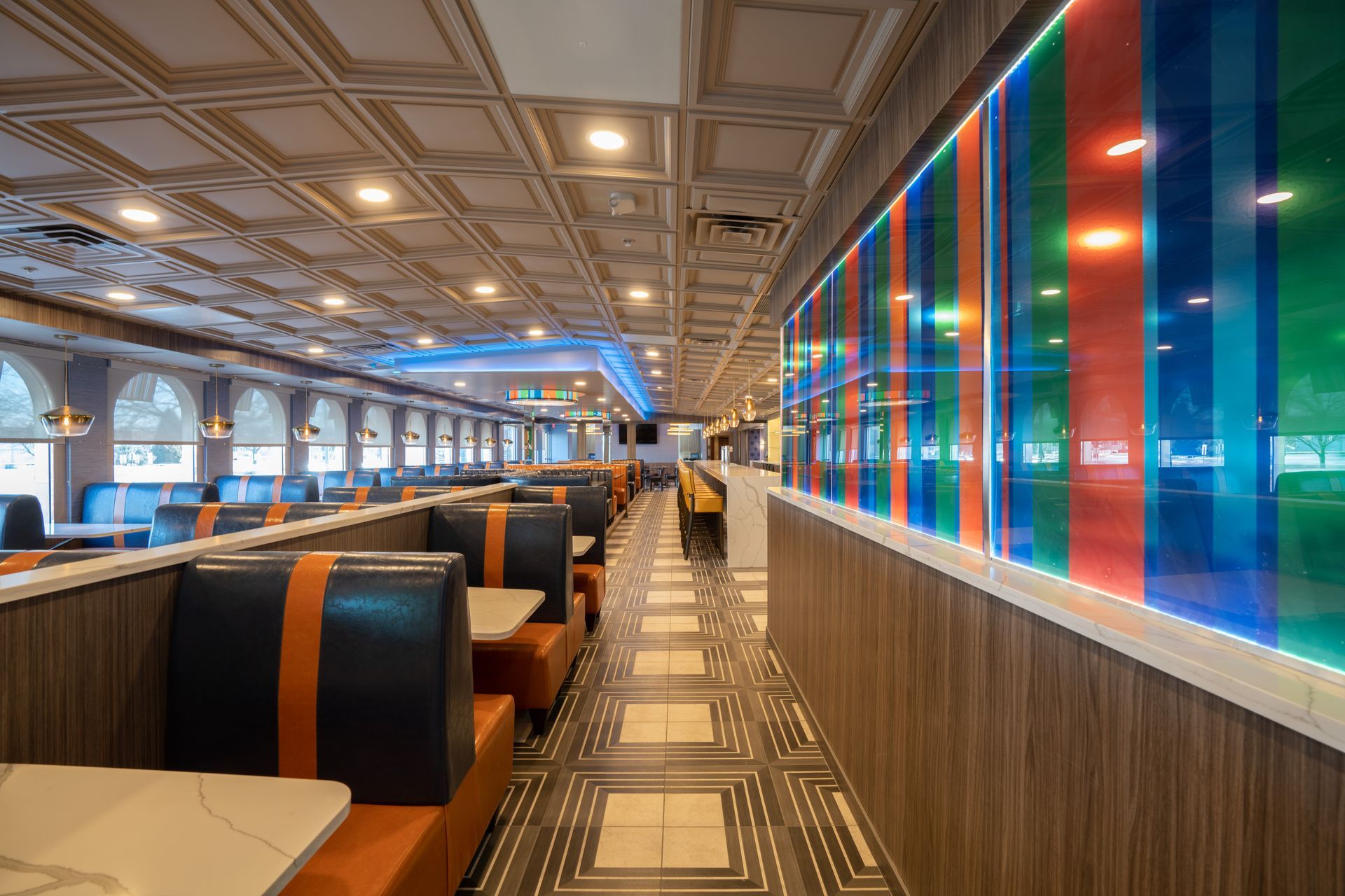 A long hallway in a diner with tables and booths.