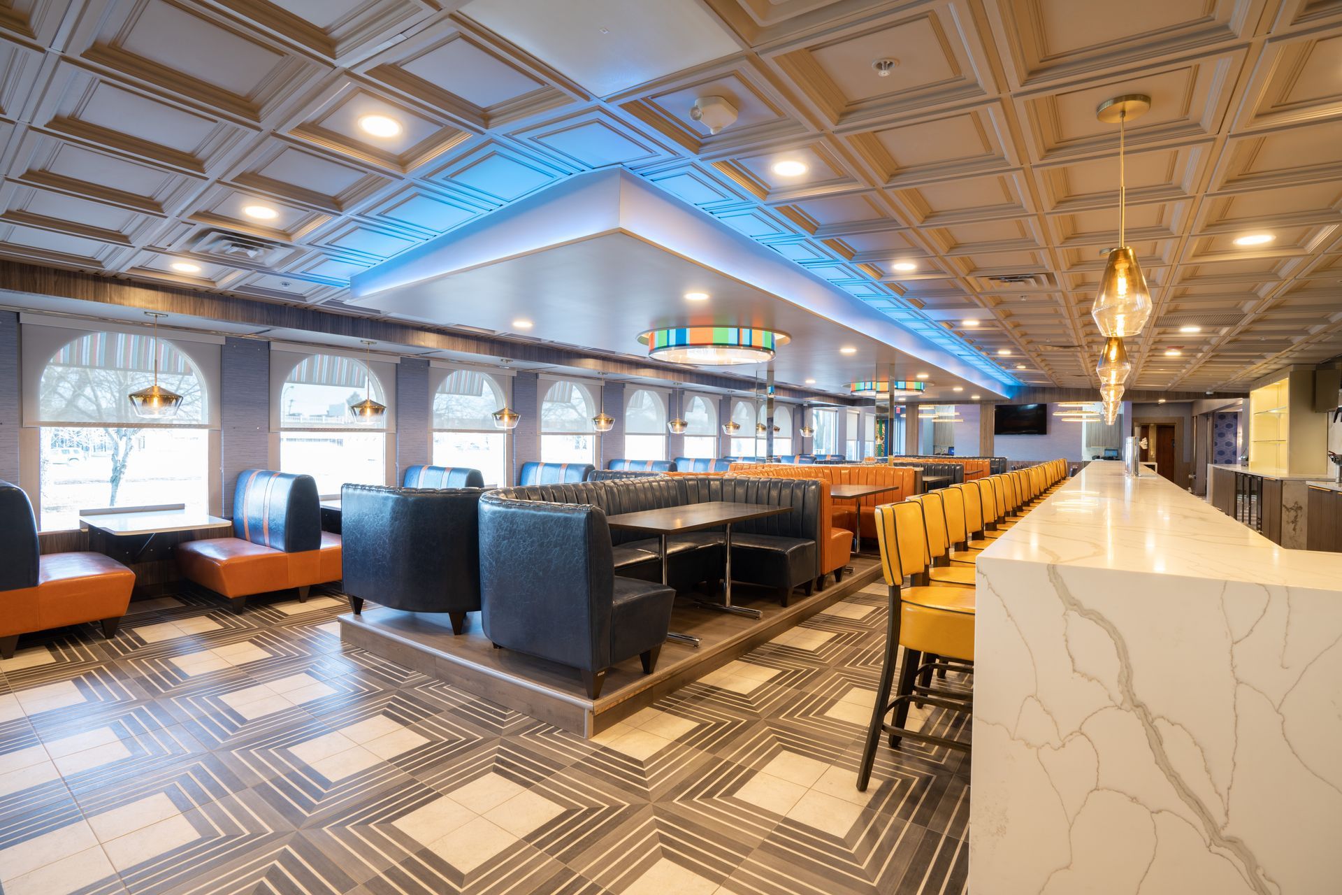 A restaurant with tables and chairs and a long bar.