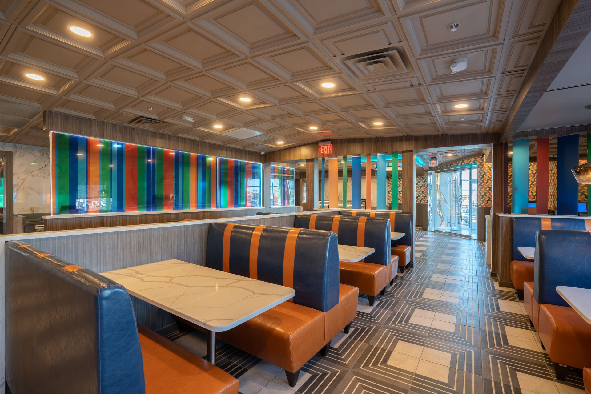 A restaurant with tables and benches and a colorful ceiling.