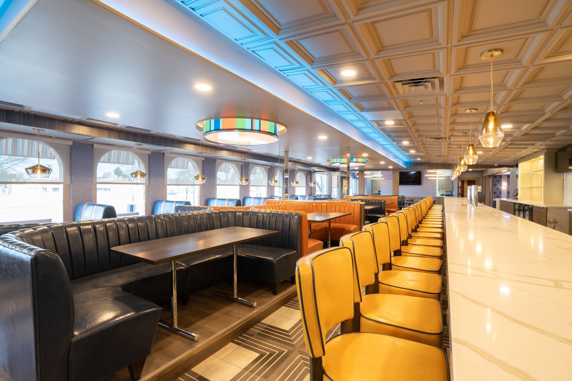 A restaurant with tables and chairs and a long bar.