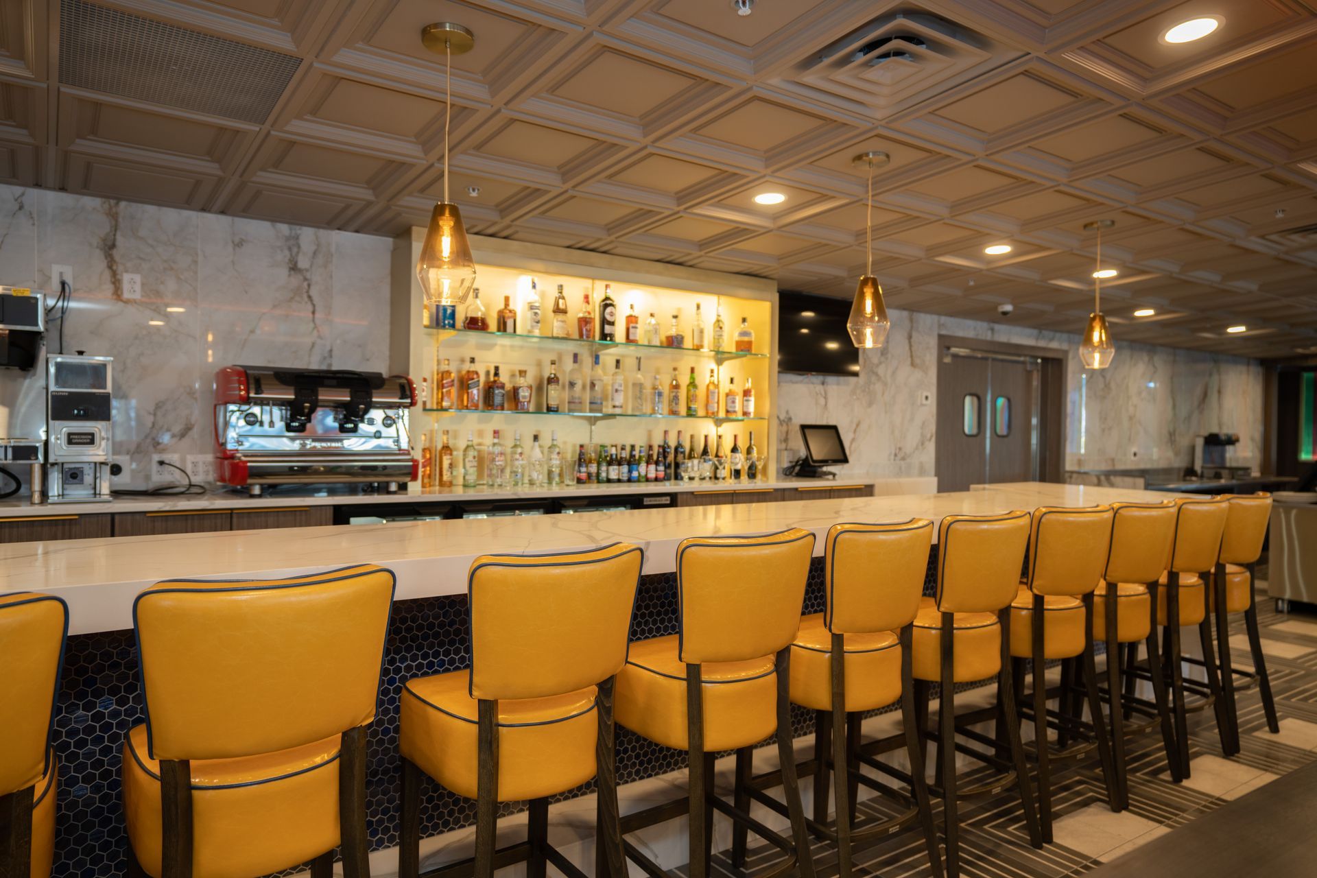 A restaurant with a long bar and yellow chairs