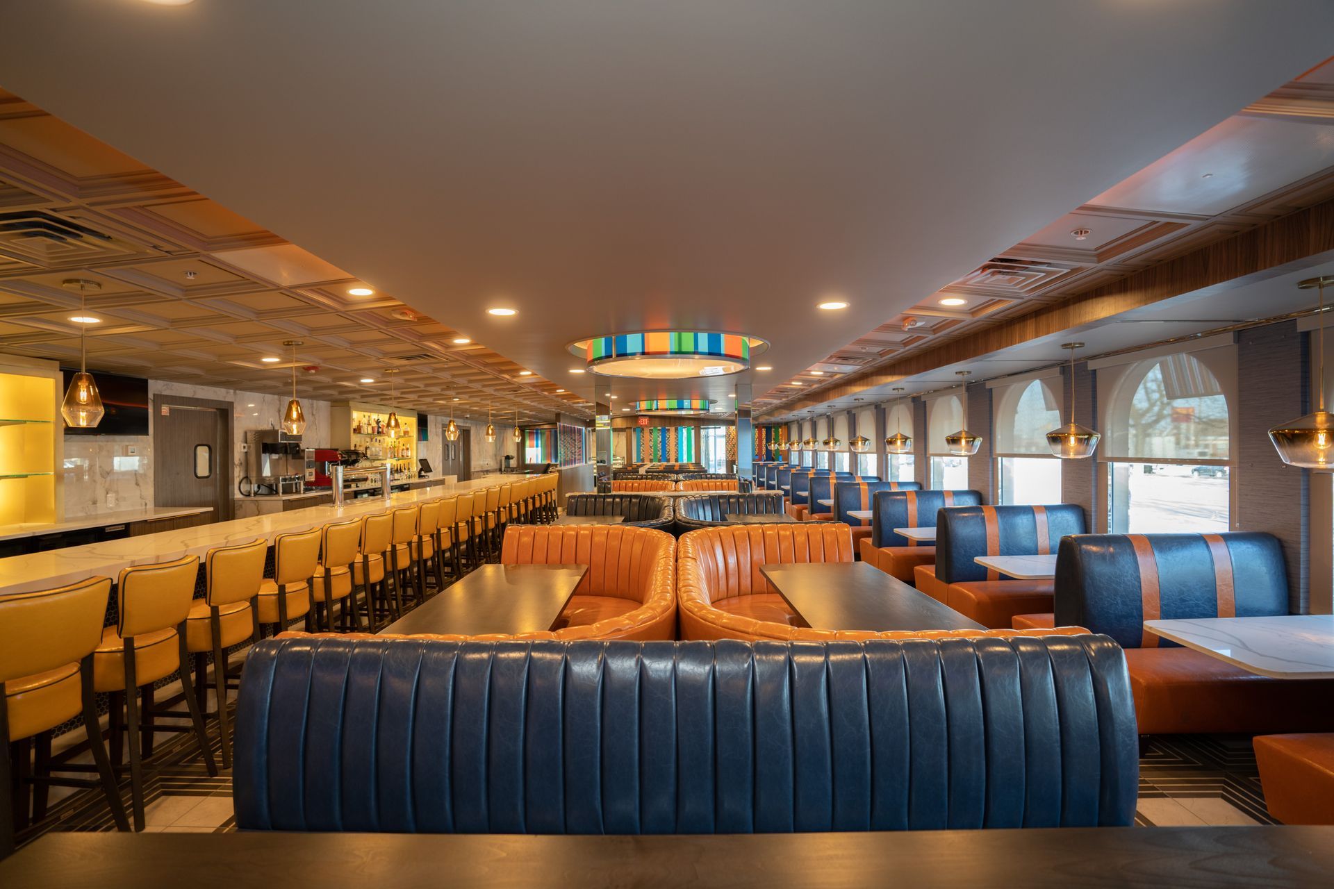 A restaurant with tables and chairs and a long bar.