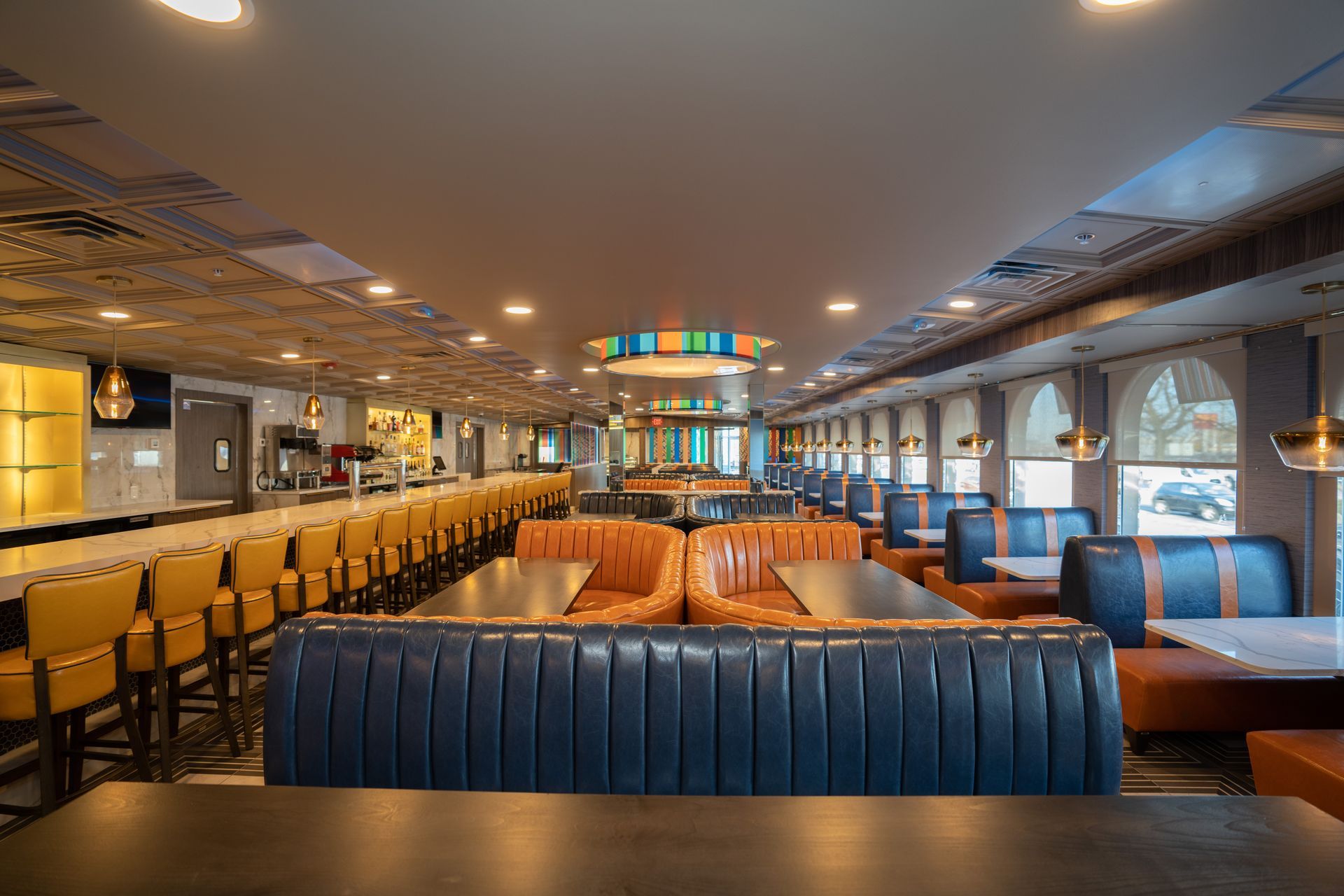A restaurant with tables and chairs and a long bar.