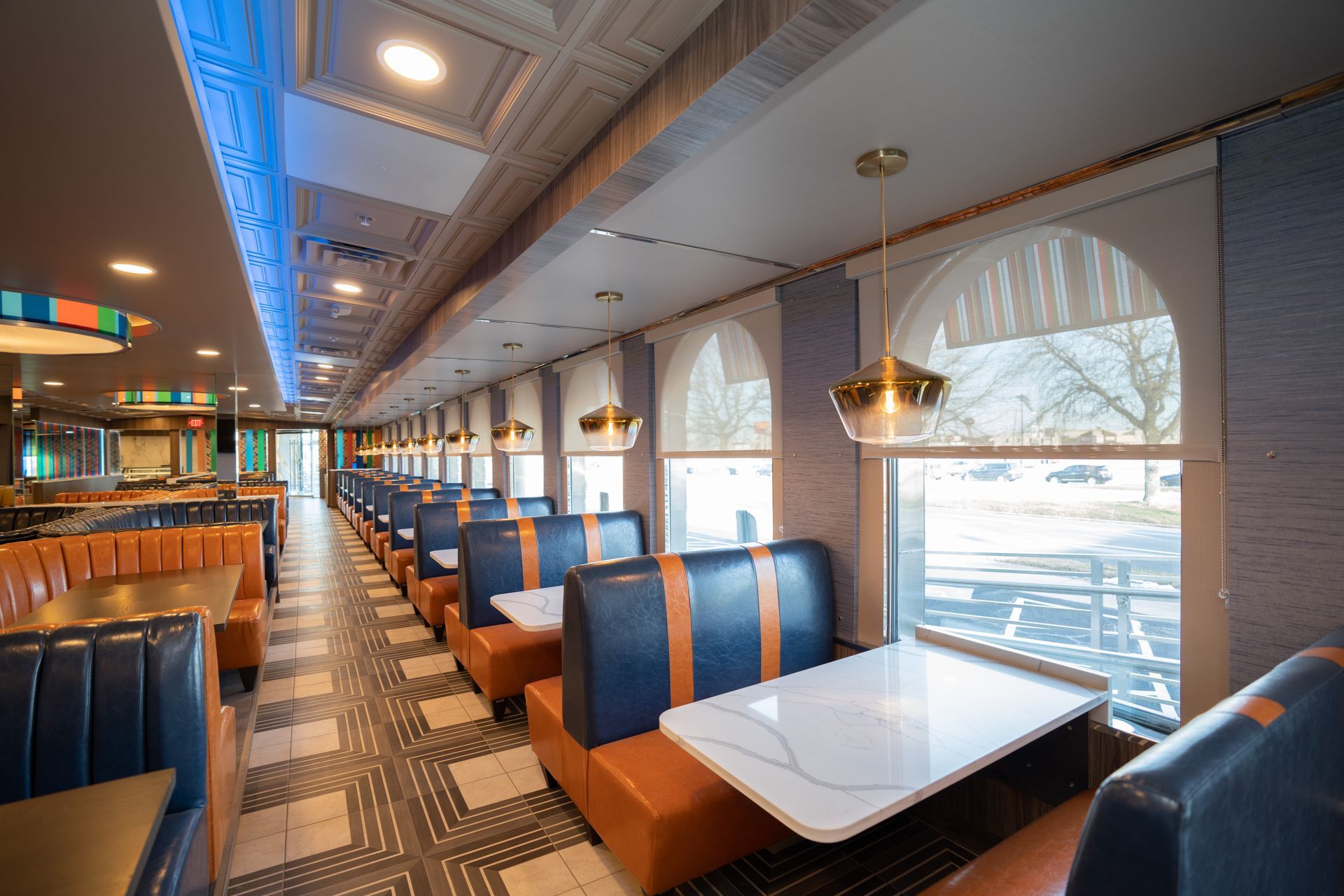 A diner with tables and benches and a lot of windows.