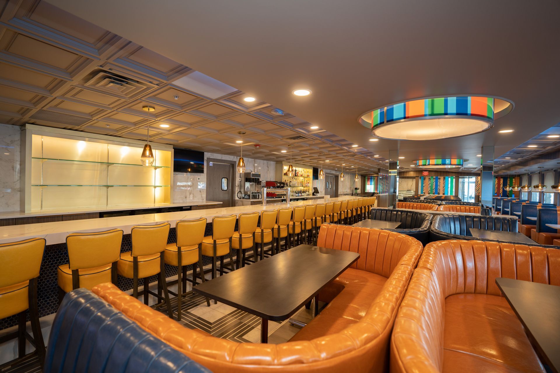 A restaurant with tables and chairs and a long bar.