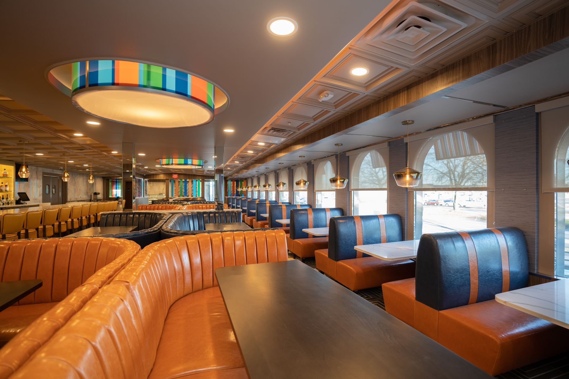 A restaurant with tables and booths and a ceiling light.