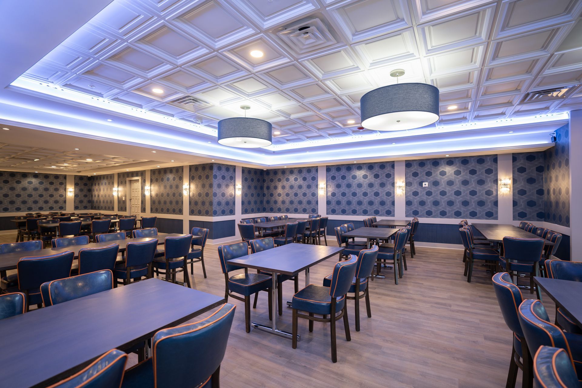 A large dining room with tables and chairs and a blue ceiling.