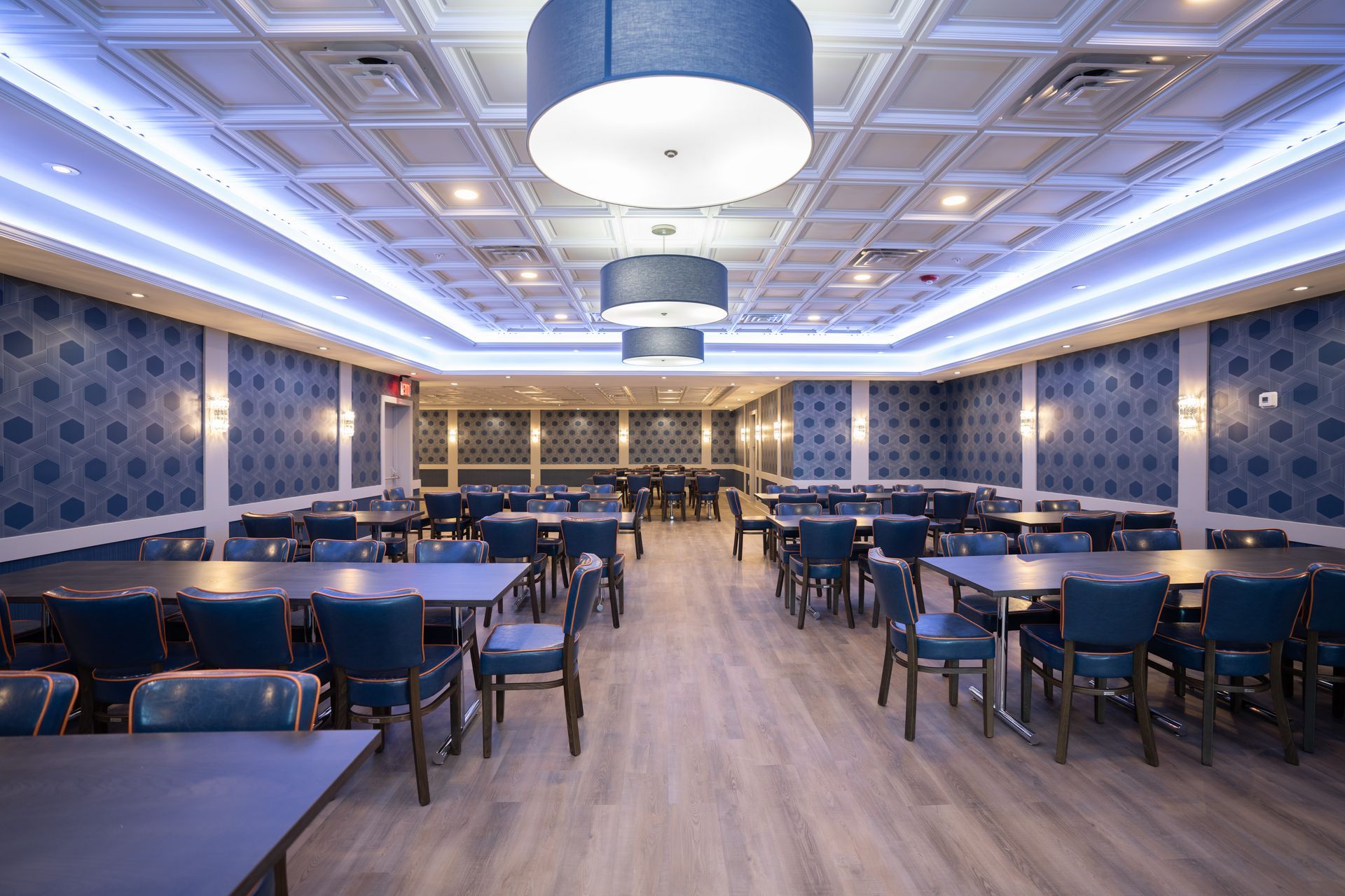 A large dining room with tables and chairs and a blue ceiling.