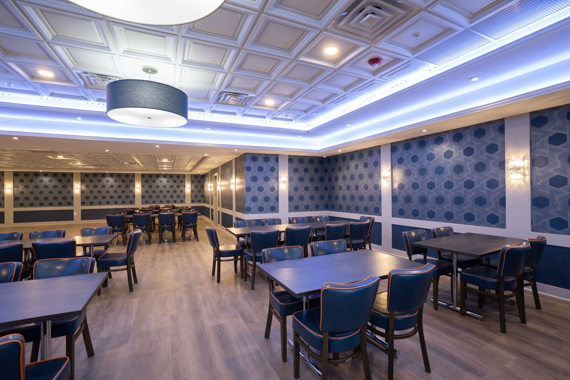 A large dining room with tables and chairs and a blue ceiling.