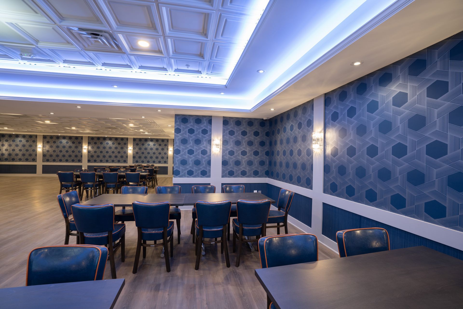 A dining room with tables and chairs and blue walls.