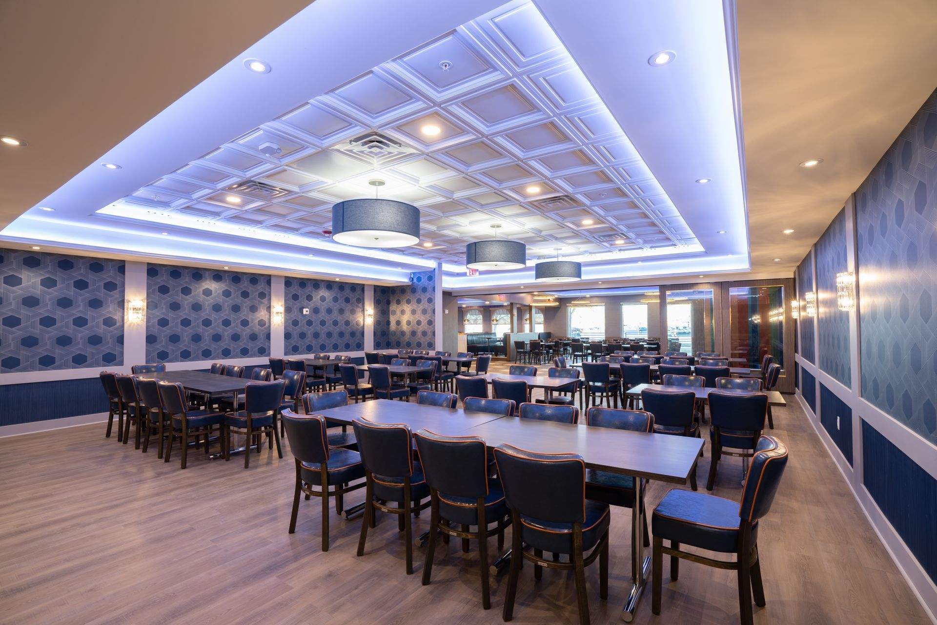 A large dining room with tables and chairs and a blue ceiling.