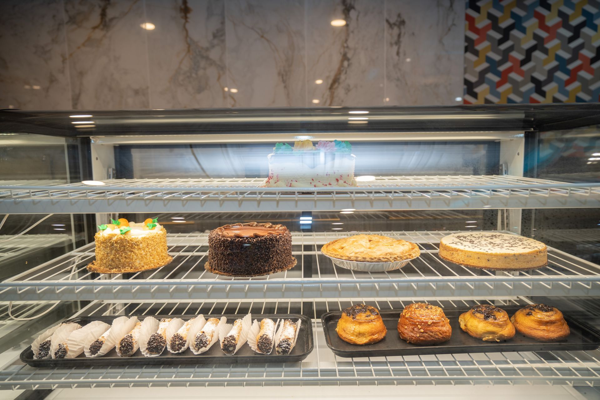 A display case filled with a variety of pastries and cakes.