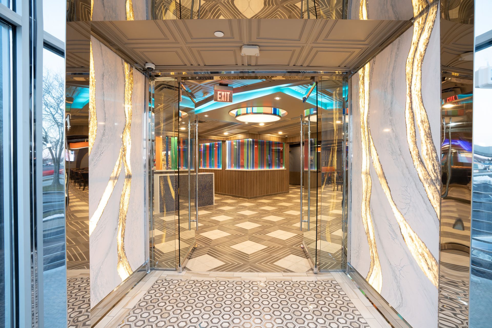 A hallway with a glass door and a patterned floor in a building.