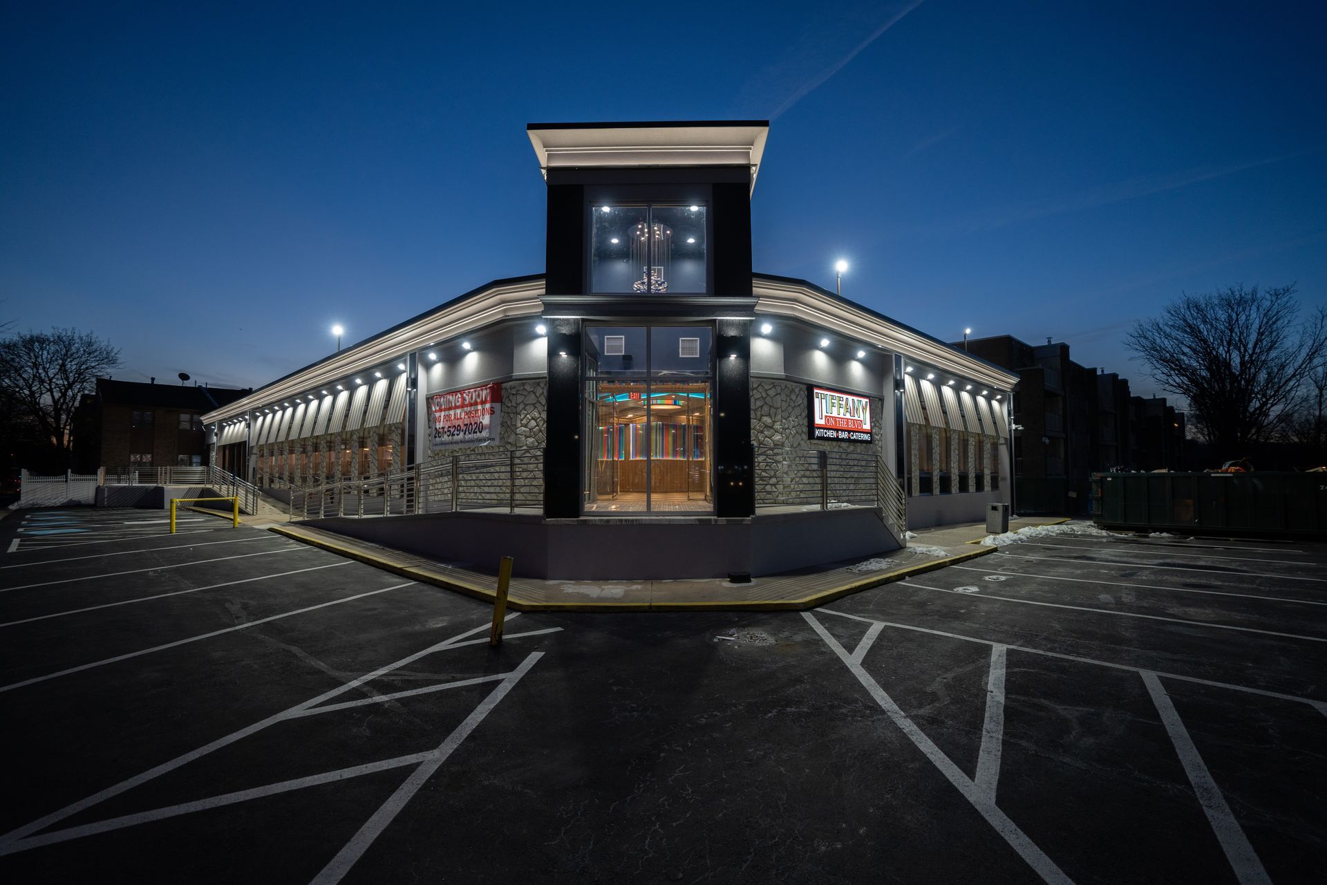 A large building with a parking lot in front of it at night