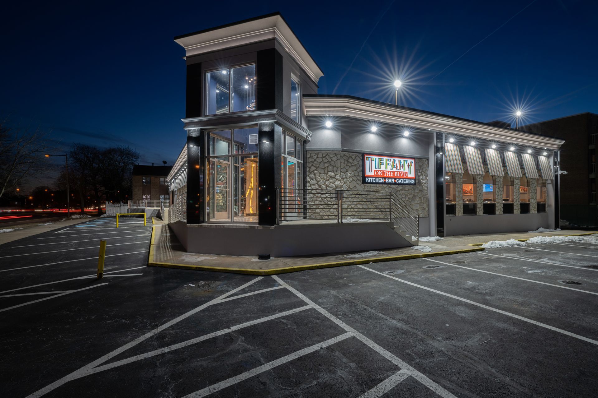 A large building with a parking lot in front of it at night.