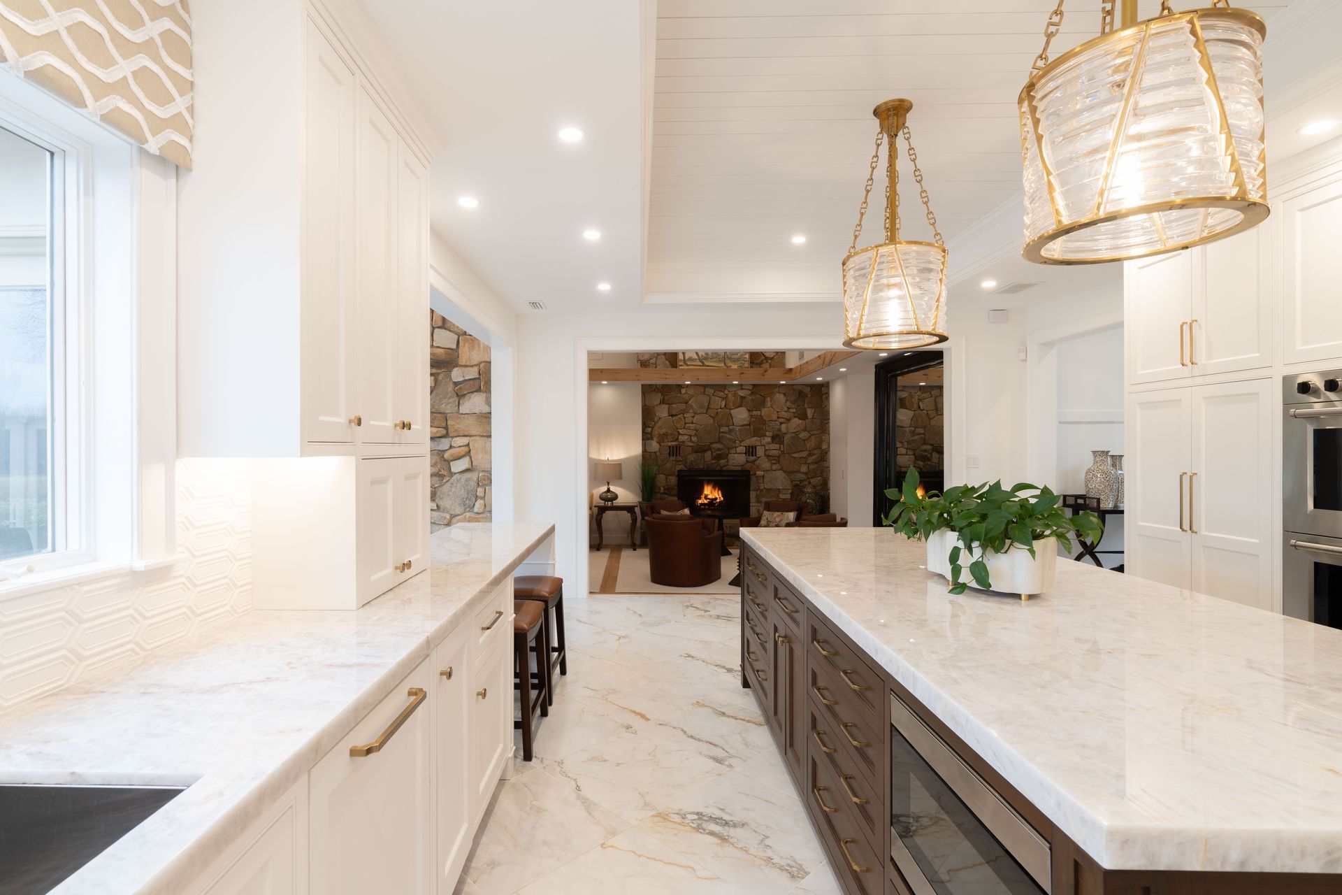 A kitchen with white cabinets and marble counter tops and a large island.