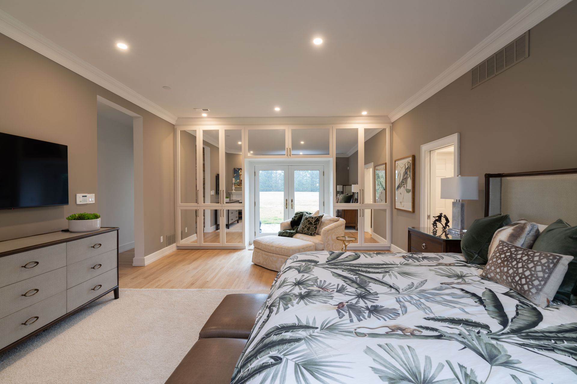A bedroom with a large bed , dresser , television and sliding glass doors.