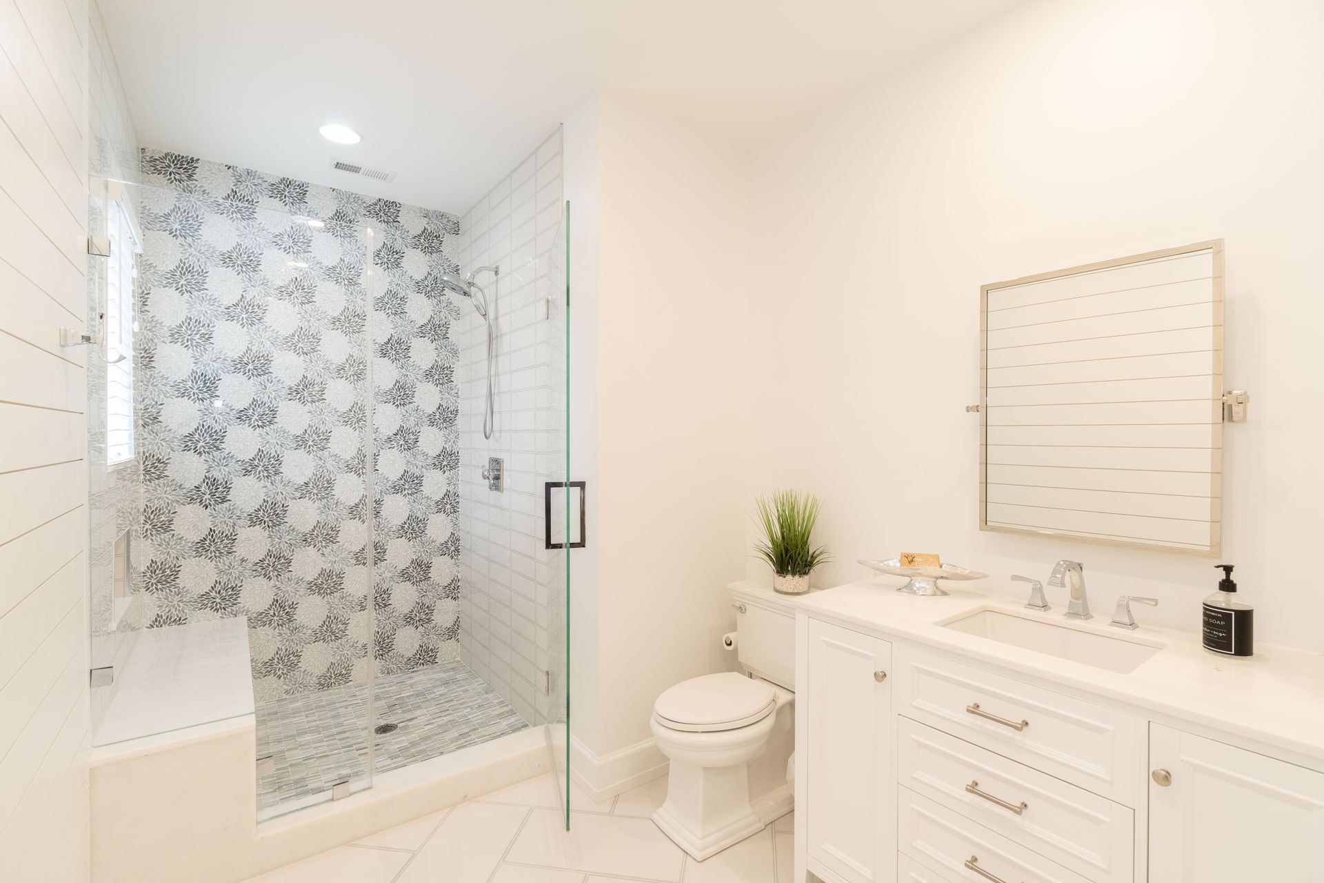 A bathroom with a toilet , sink , mirror and walk in shower.