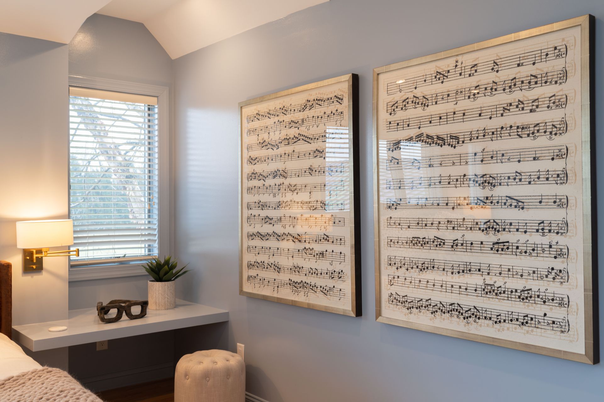 A bedroom with two paintings of sheet music on the wall.