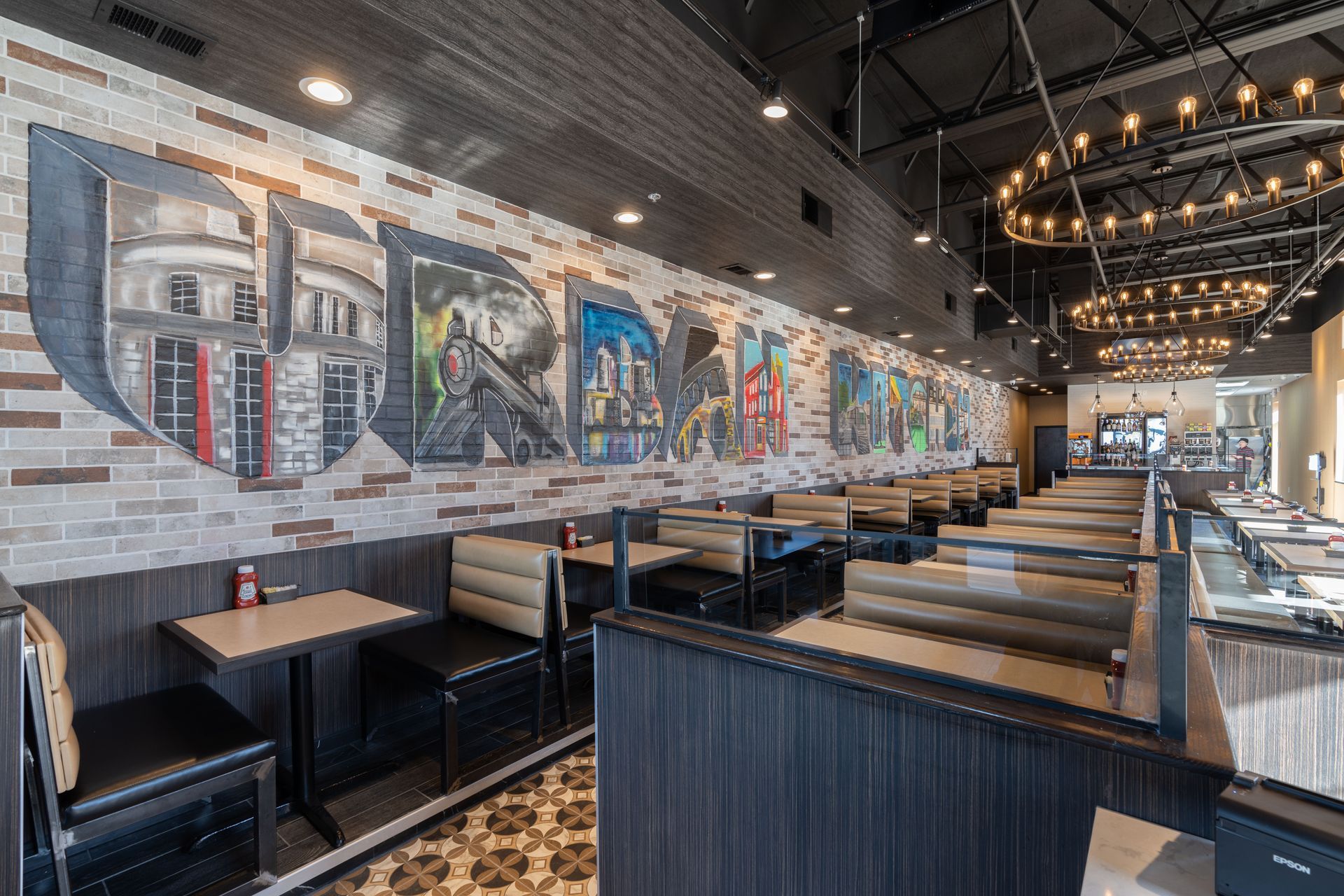 A restaurant with tables and booths and a large mural on the wall.