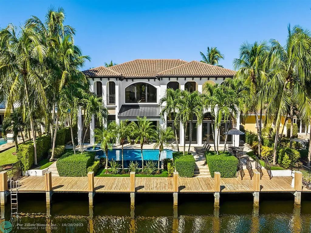 A large house with a dock in front of it surrounded by palm trees.