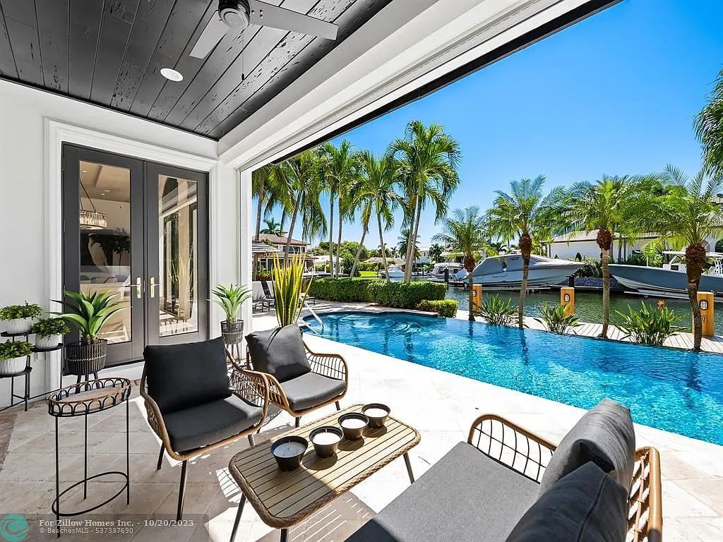 A patio with a couch , chairs and a table next to a pool.