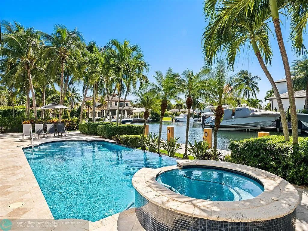 A large swimming pool with a hot tub in the middle of it surrounded by palm trees.