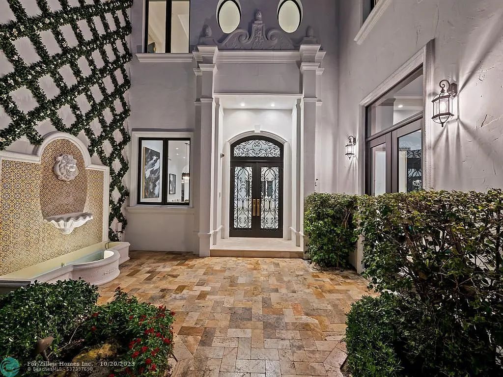 The front door of a house with a fountain in front of it.