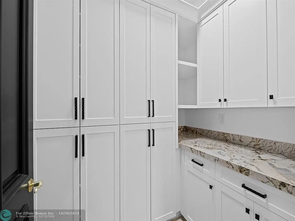 A kitchen with white cabinets and granite counter tops.