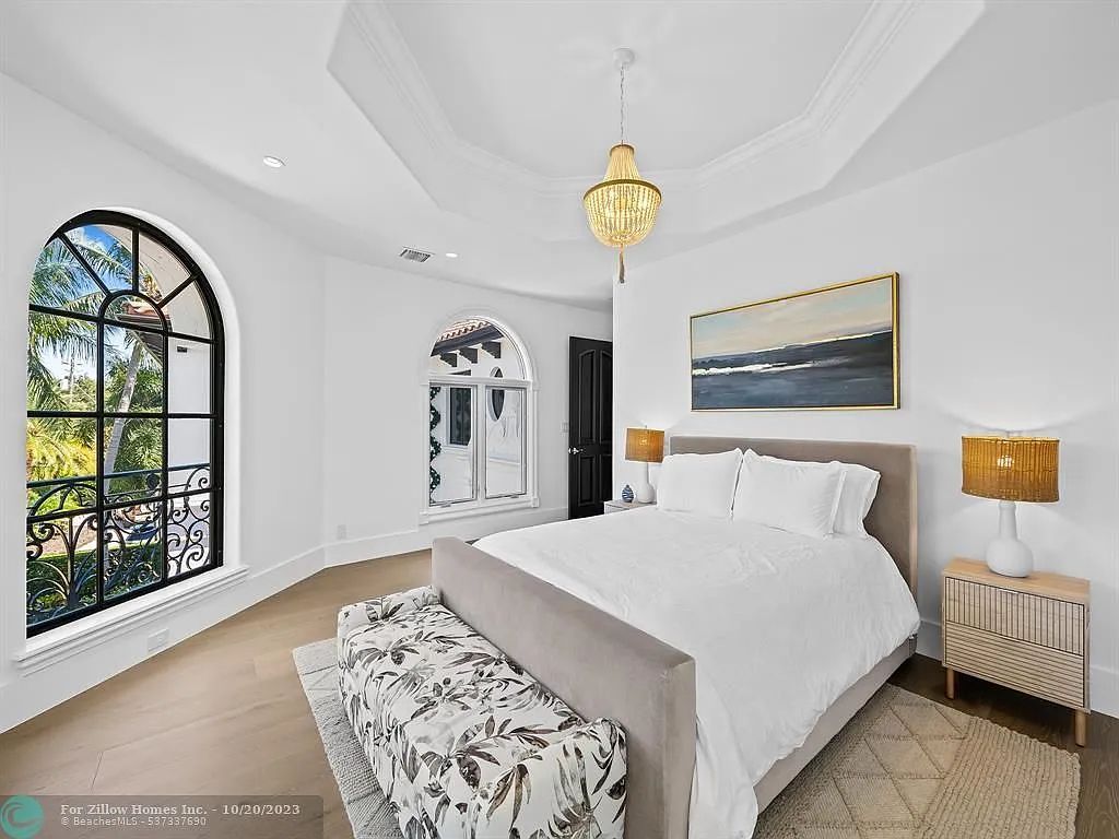 A bedroom with a bed , nightstand , lamps and a large window.