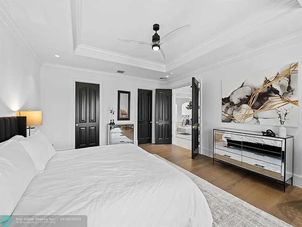 A bedroom with a bed , dresser , mirror and ceiling fan.
