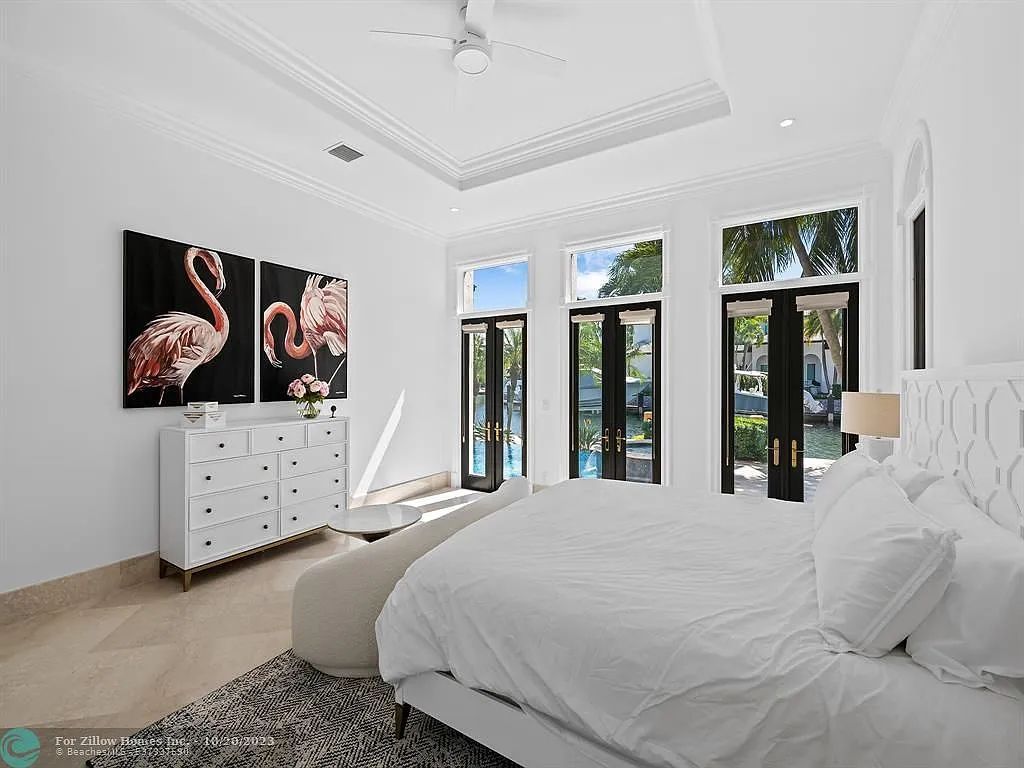 A bedroom with a bed , dresser , paintings and a ceiling fan.