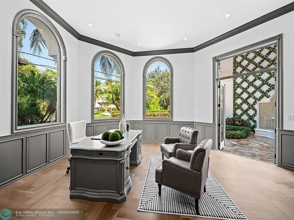 A living room with a desk , chairs , and a rug.