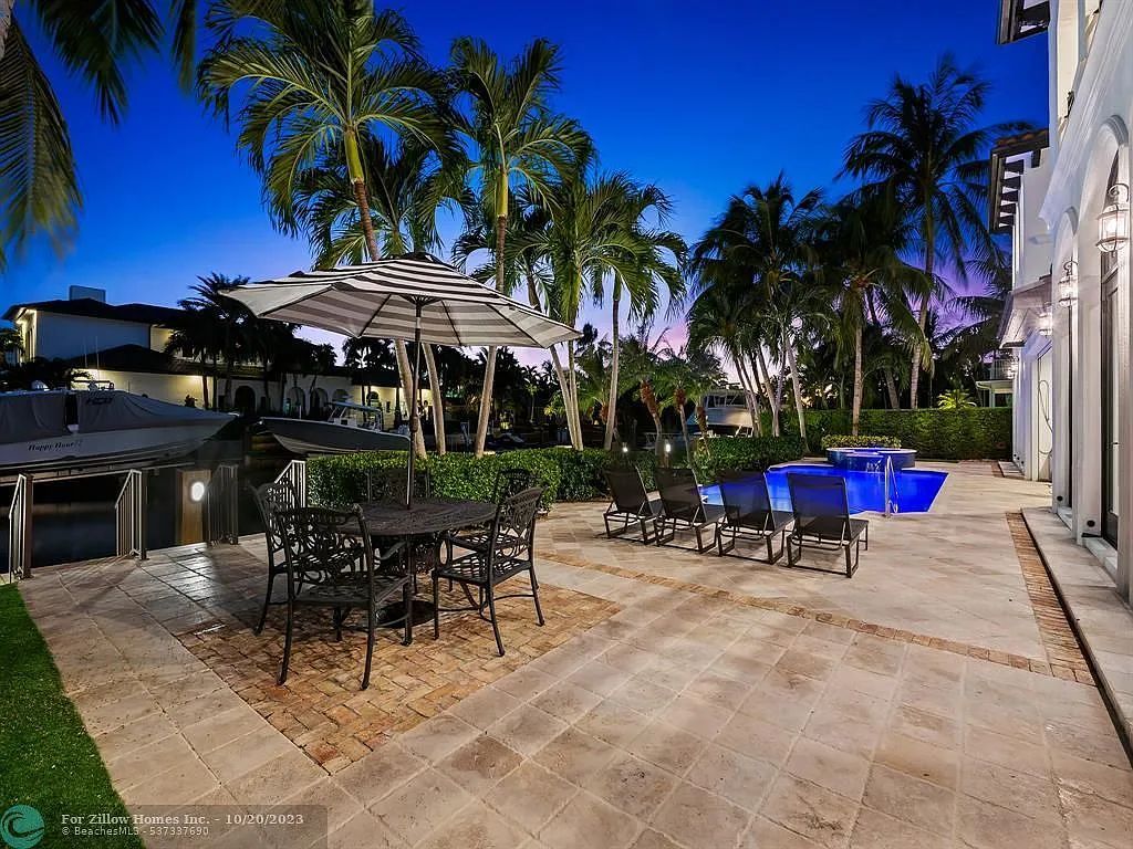 A patio with a table and chairs and an umbrella in front of a pool.