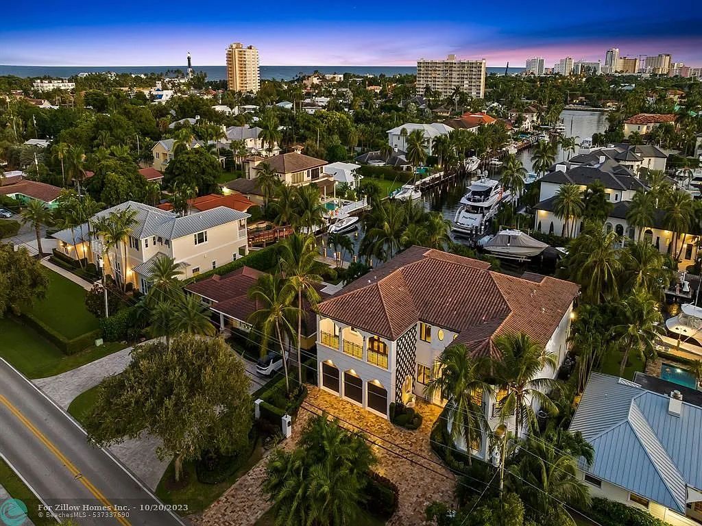 An aerial view of a large house in a residential area surrounded by palm trees.
