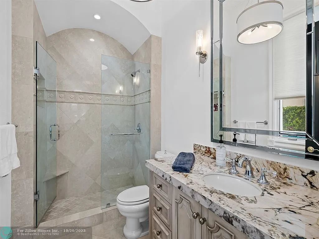 A bathroom with a toilet , sink , shower and mirror.