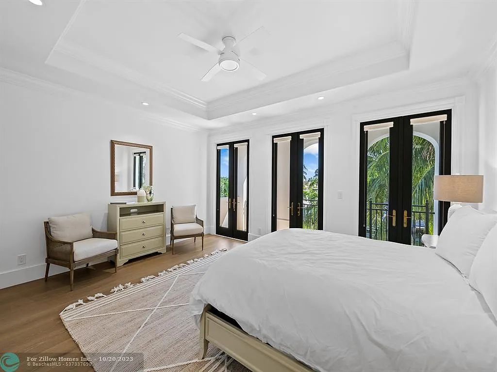 A bedroom with a bed , dresser , chairs and a ceiling fan.