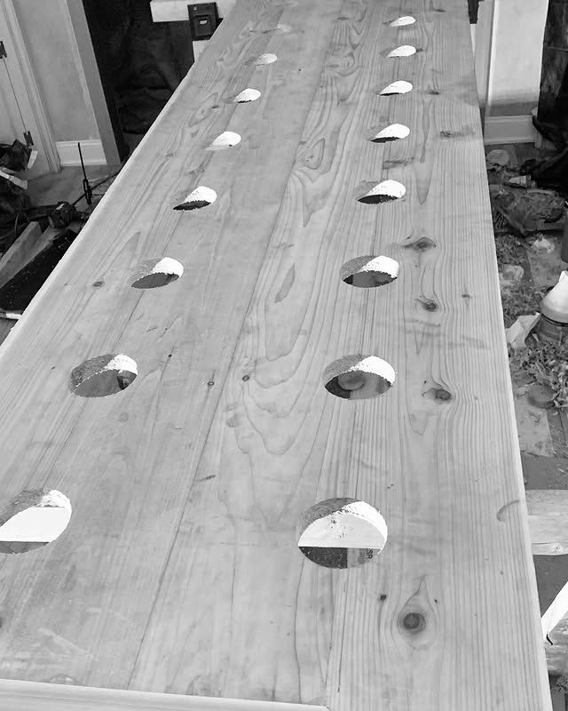A black and white photo of a wooden table with holes in it.