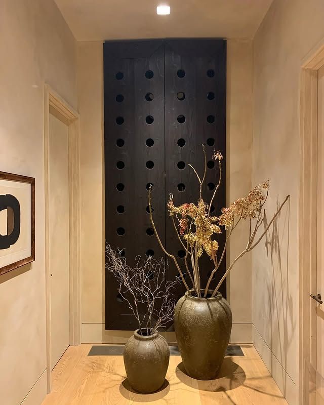 There are two vases with flowers in them in a hallway.