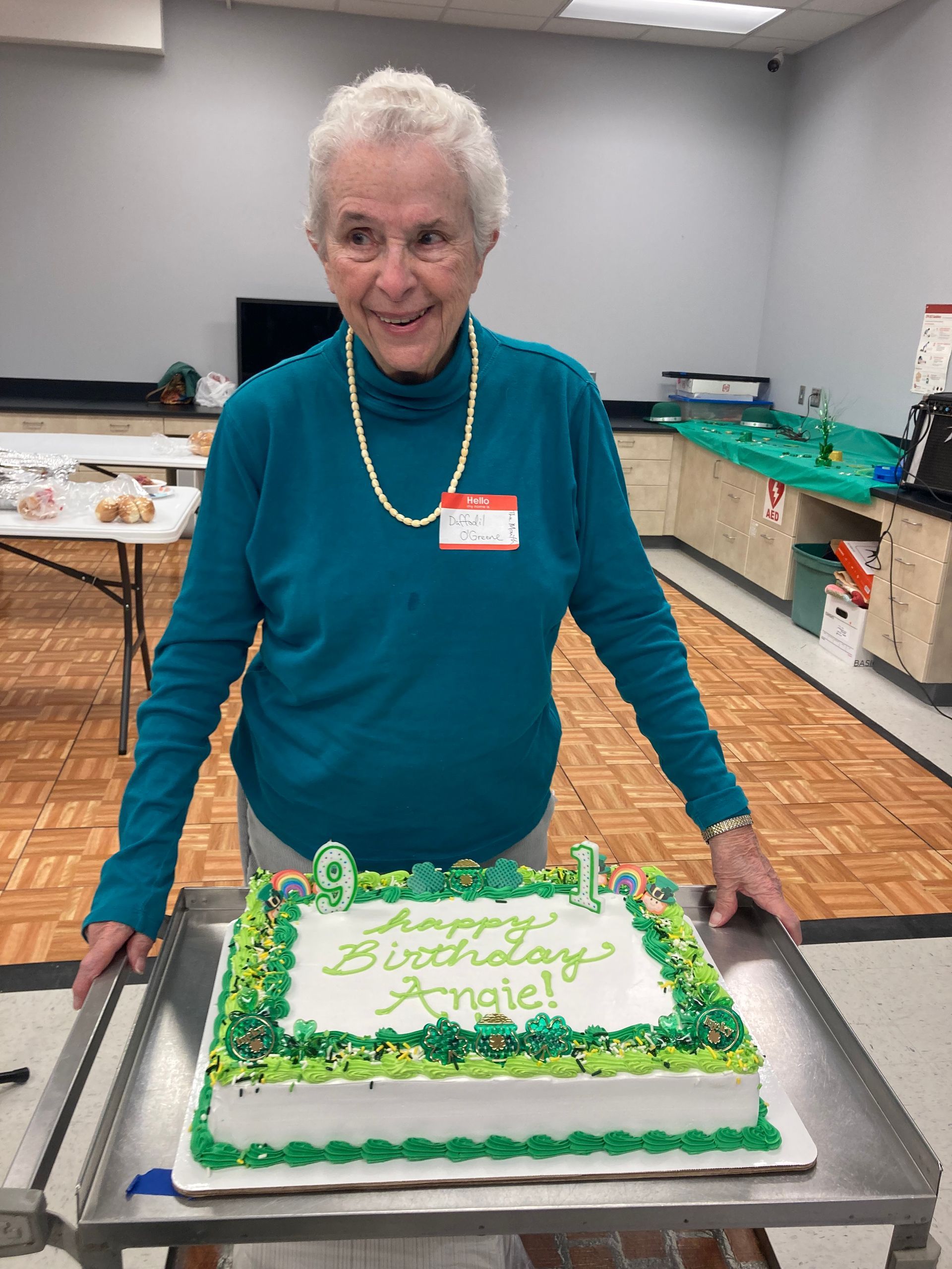 A woman in a blue shirt is holding a birthday cake