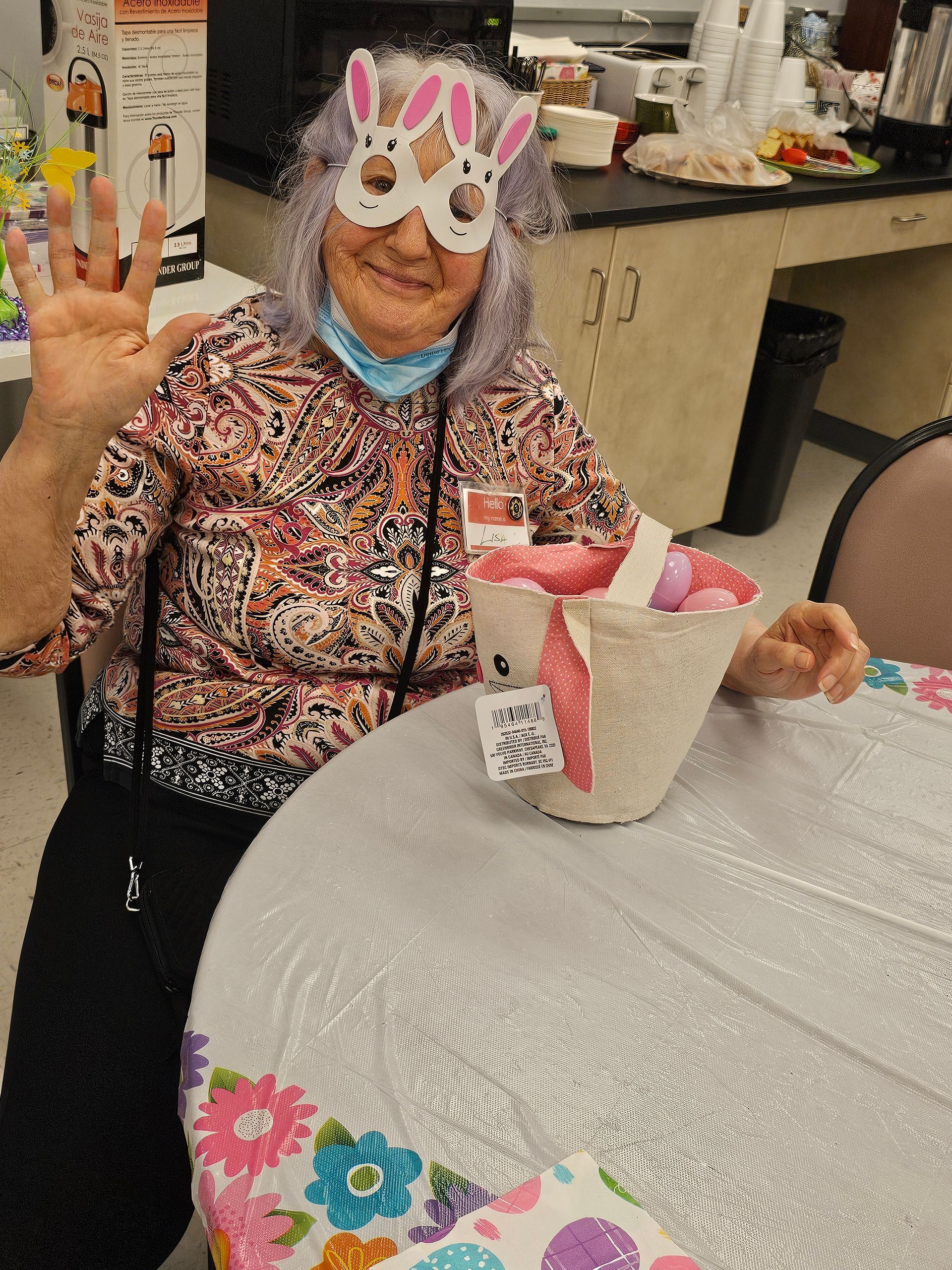 A woman wearing a bunny mask is sitting at a table.