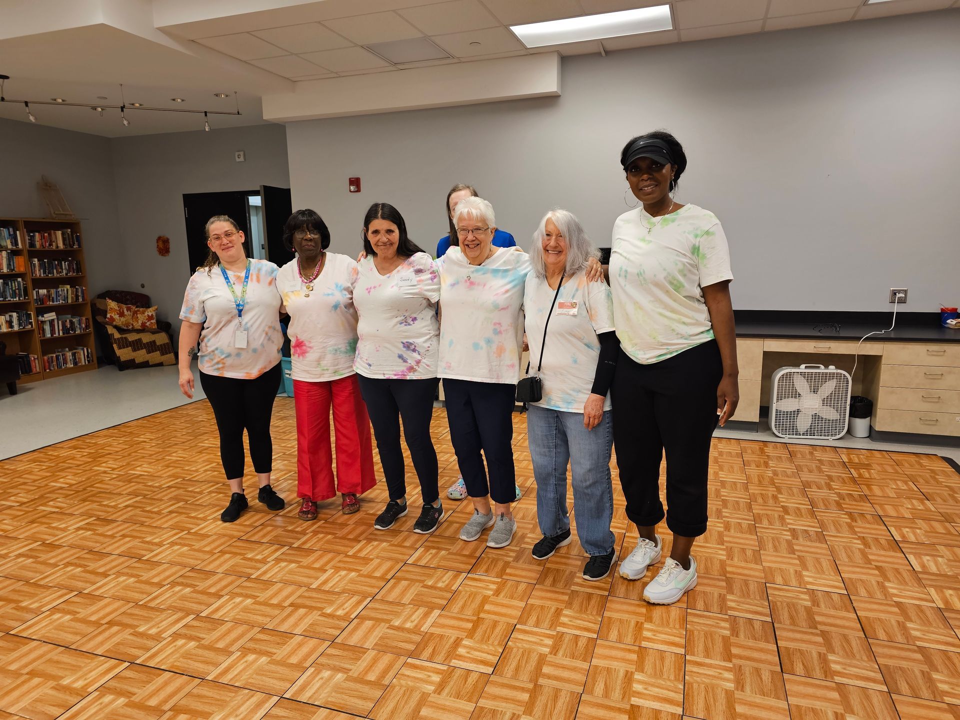 A group of older women are standing next to each other on a dance floor.