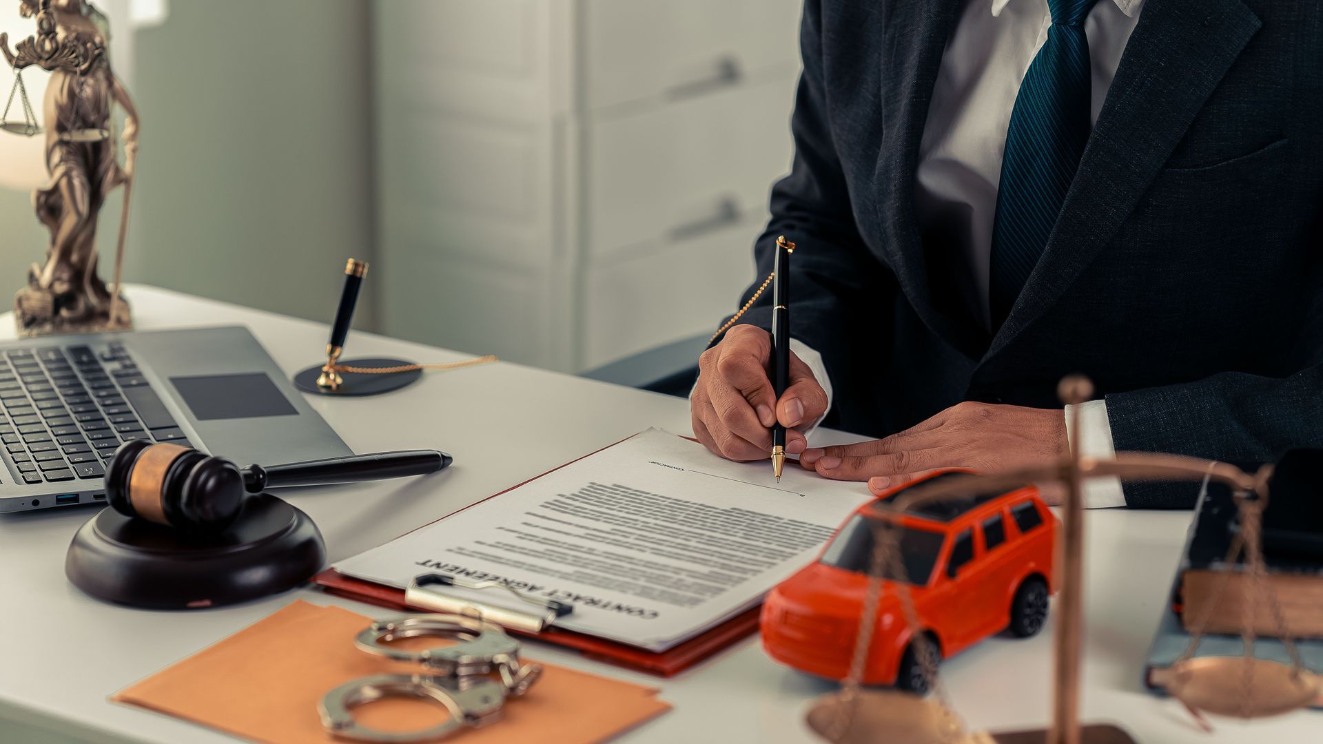 A small red toy car sits next to a judge's gavel.
