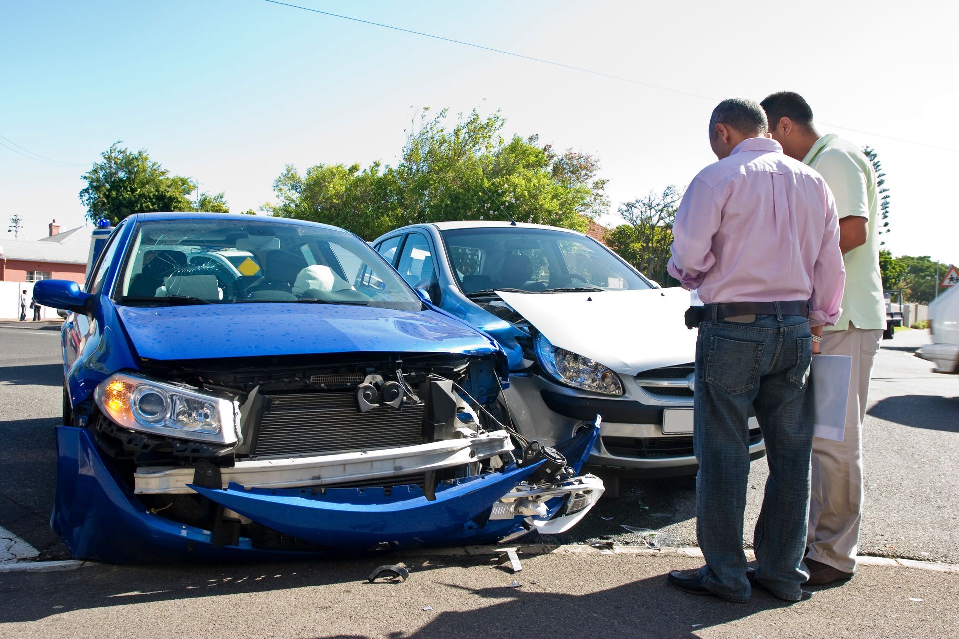 Two men are conferring next to their two smashed cars.