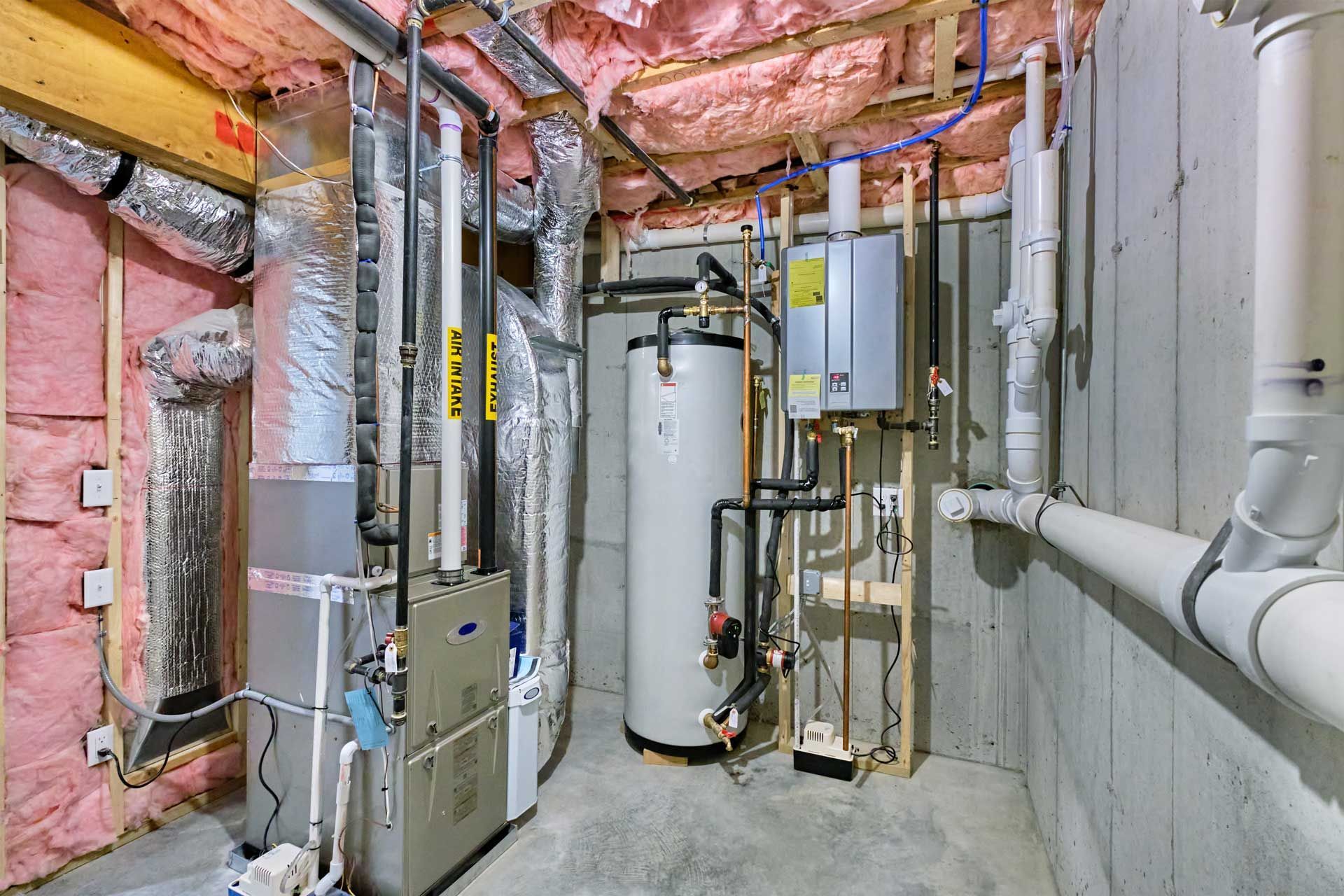 Basement with HVAC system, water heater, ductwork, pipes, and pink insulation.