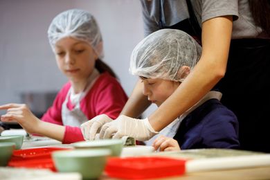 A woman is helping a child with a plastic cap and gloves. A woman is helping a child with a plastic cap and gloves.