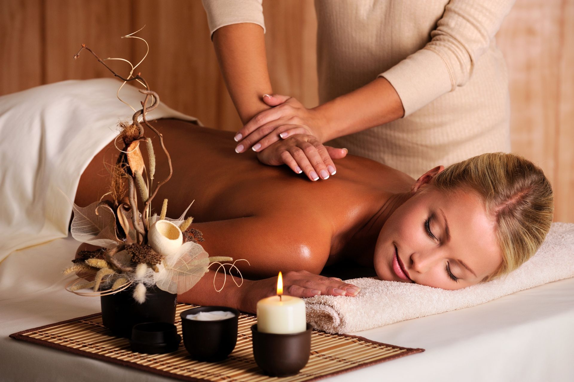 A woman is getting a massage with flowers and candles in the background