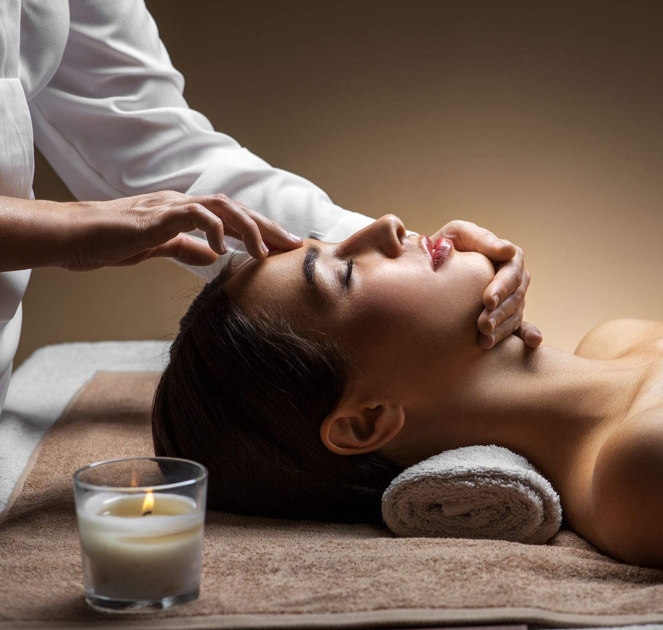 A woman is getting a massage at a spa next to a candle